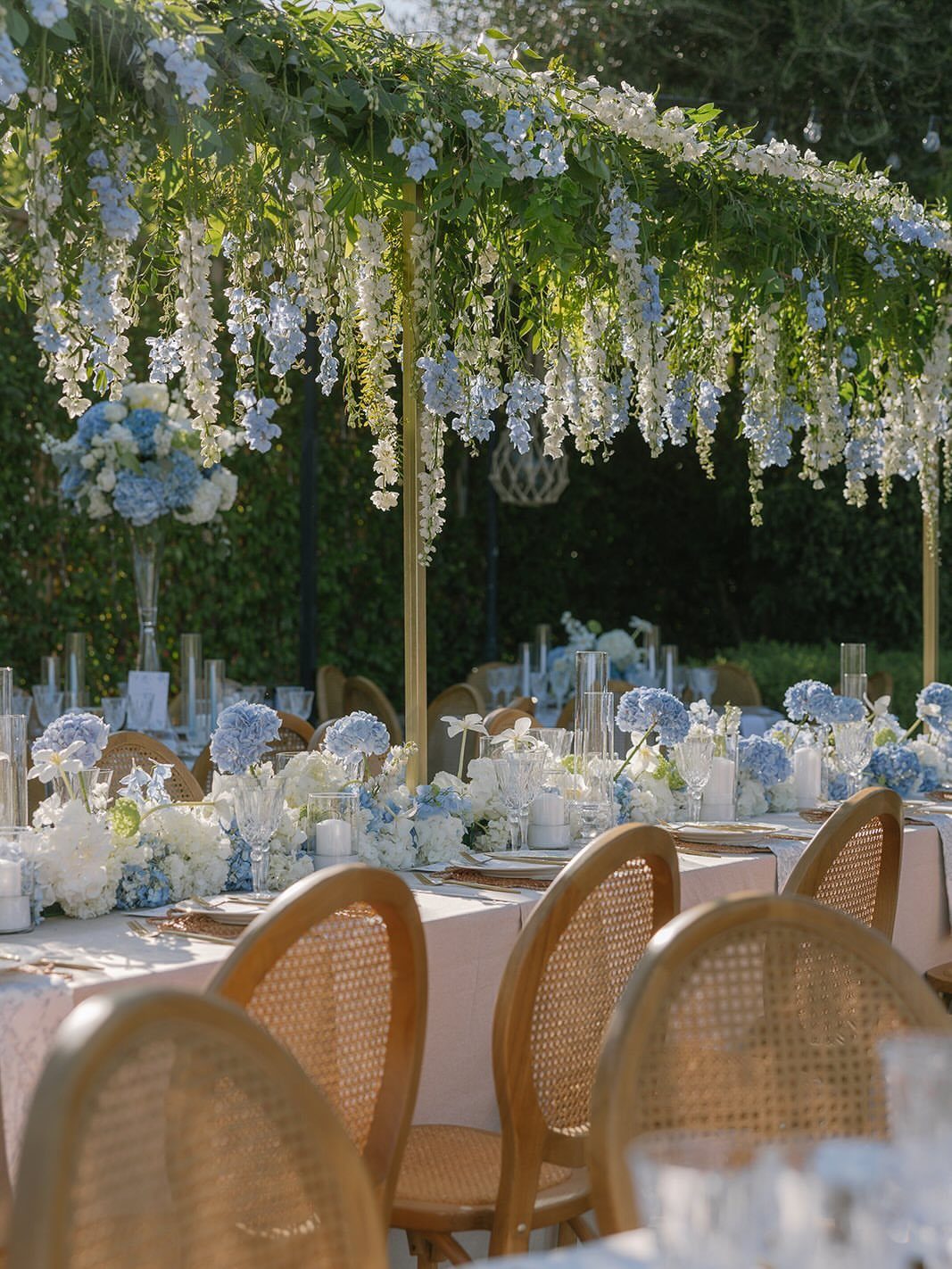 10 Blue Color Palette Wedding Ideas for Every Season 2 Wedding table decorated with baby blue hydrangeas, white flowers, and ivory linens under hanging wisteria.