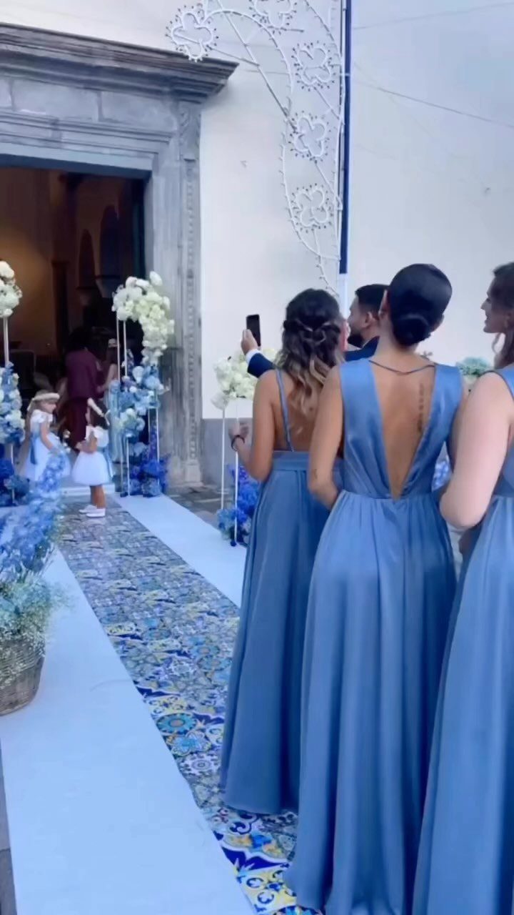 10 Blue Color Palette Wedding Ideas for Every Season 4 Bridesmaids in long blue satin dresses standing on a blue patterned tile wedding runner.