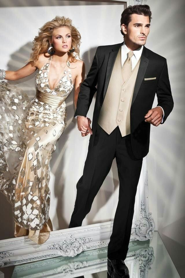 A man in a black tuxedo and a woman in a champagne patterned gown posing together.