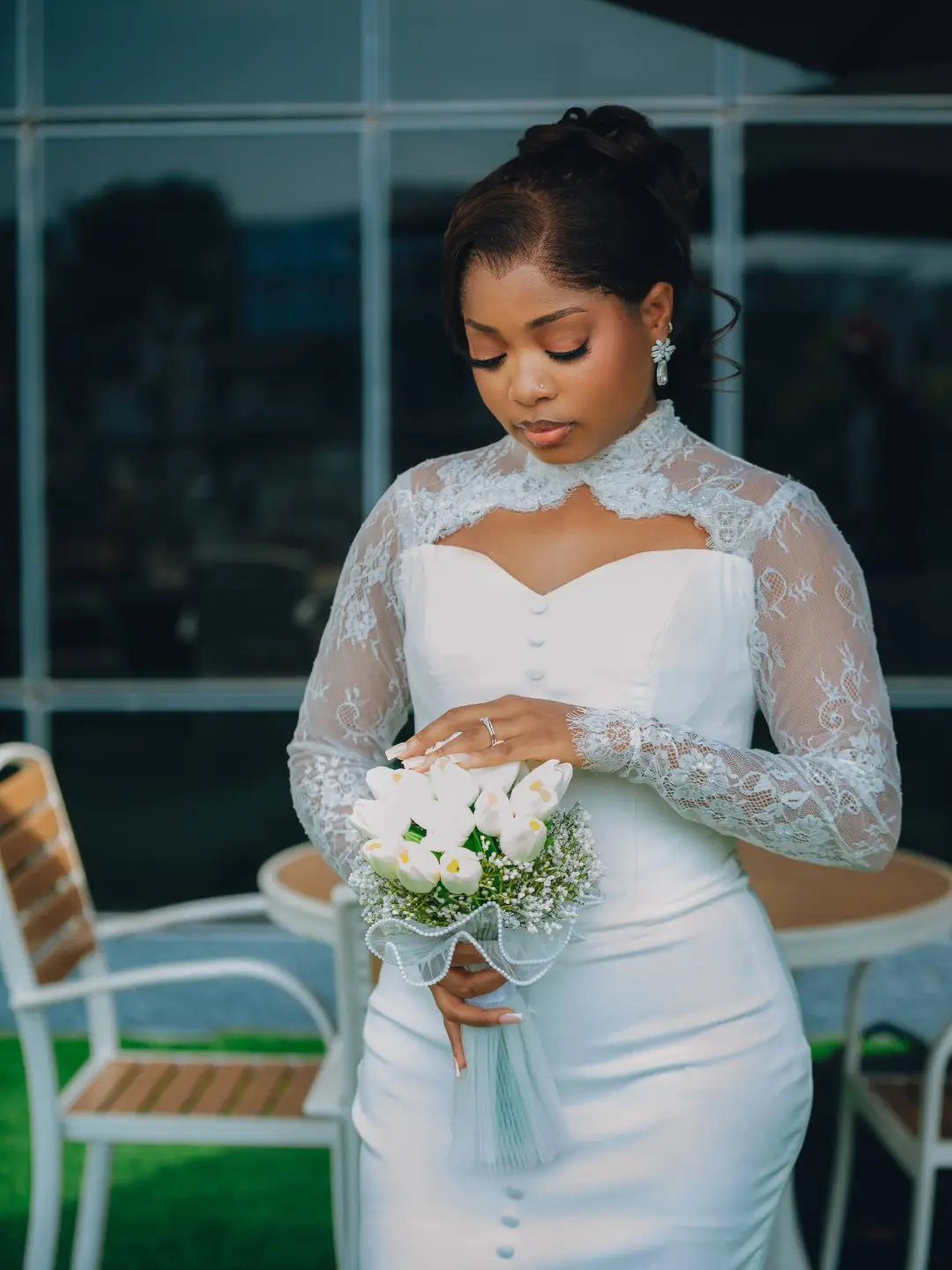 Woman in a white lace wedding dress holding a bouquet of white flowers.