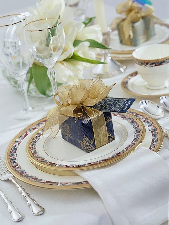 Elegant dinnerware with gold rims and silver cutlery set on a white linen tablecloth.