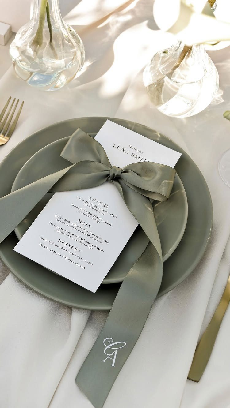 A sage green plate with a white menu card tied by a large satin ribbon.