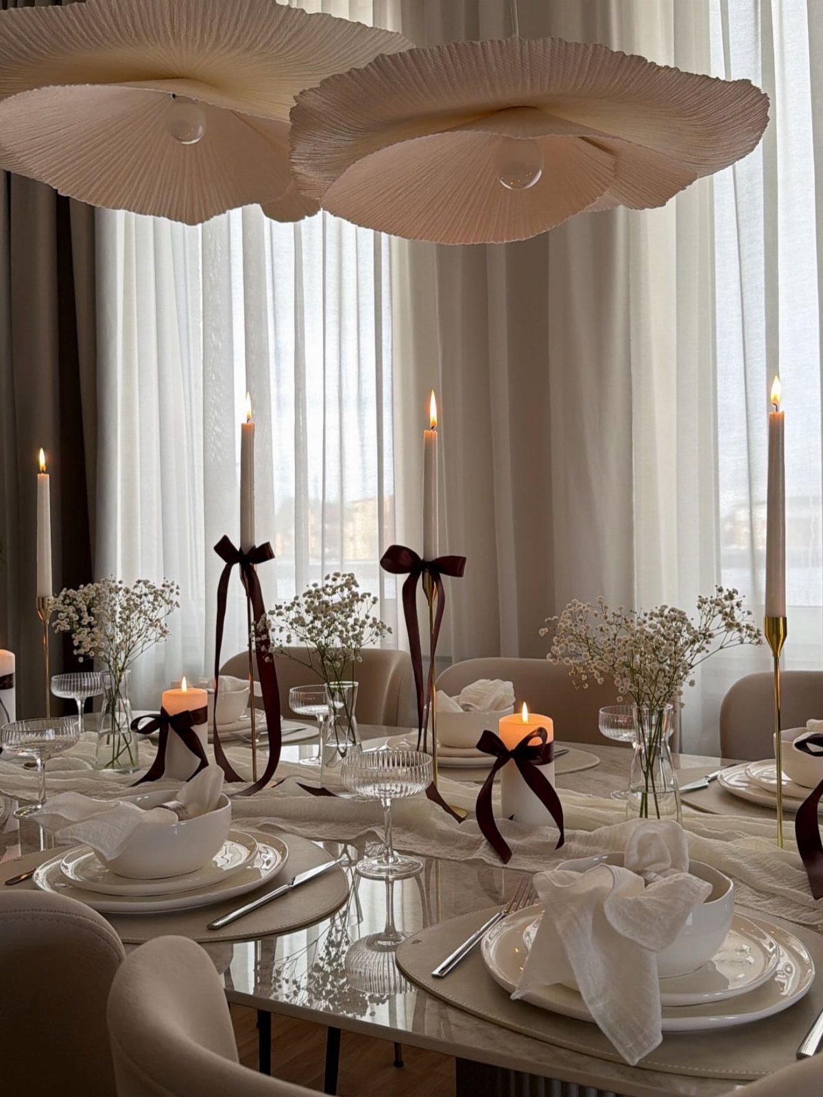 Tall taper candles and small orange candles decorate an elegant, formal dining table setting.