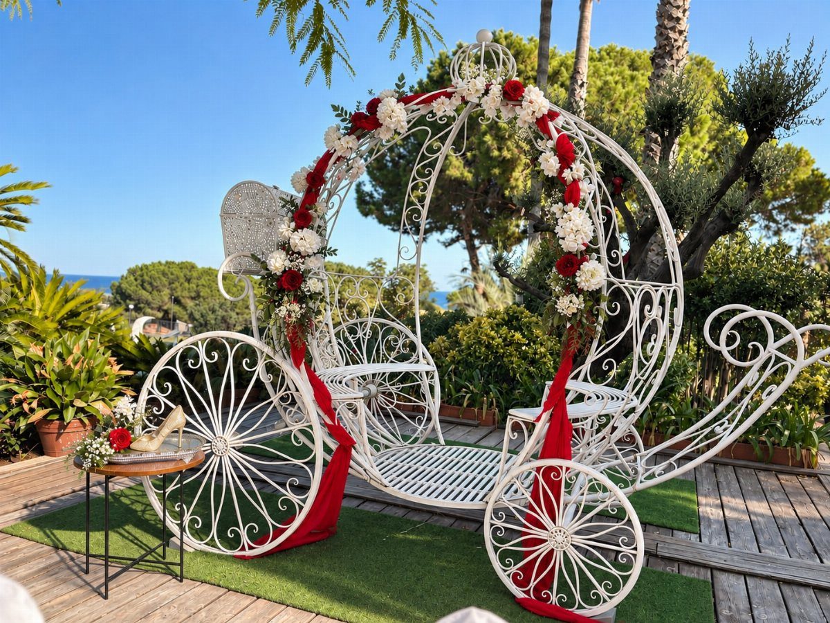 A white decorative metal carriage decorated with red and white flowers on a wooden deck.