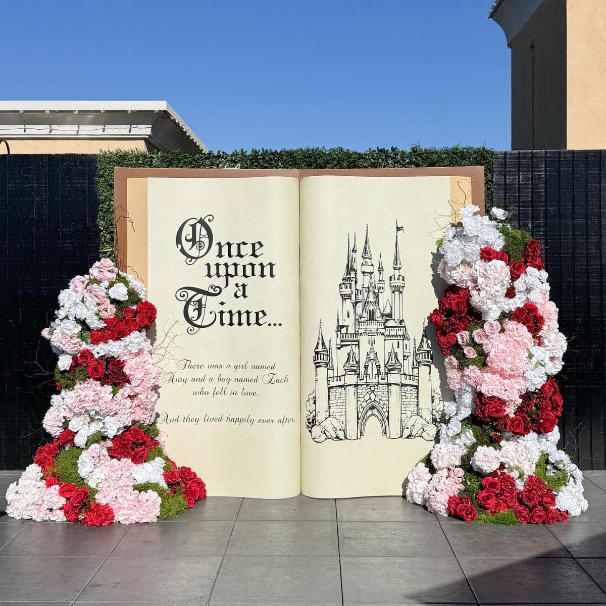 Large open storybook prop with castle illustration and pink floral arrangements on either side.