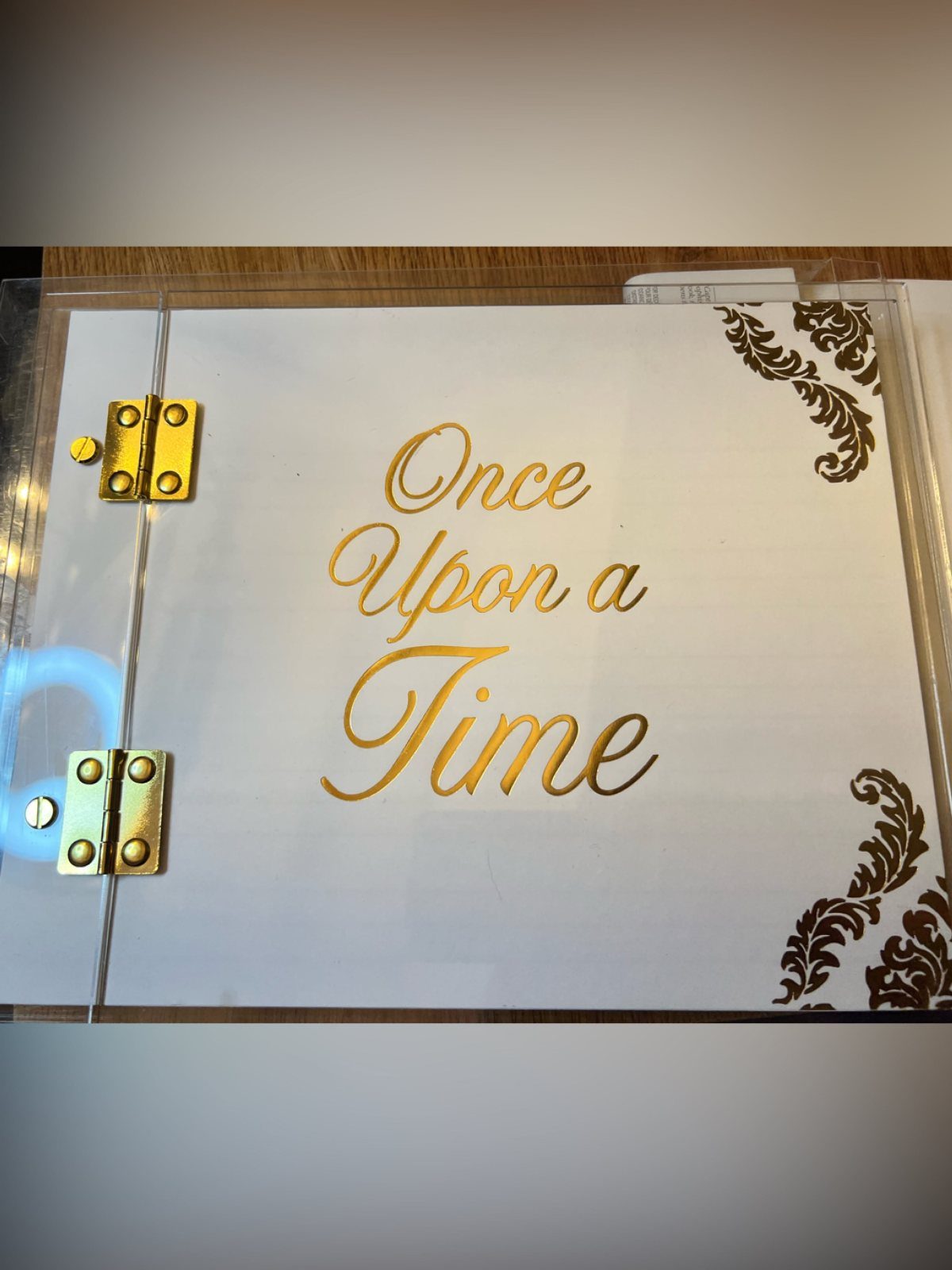 A white book with gold lettering reading Once Upon a Time and gold corner flourishes.