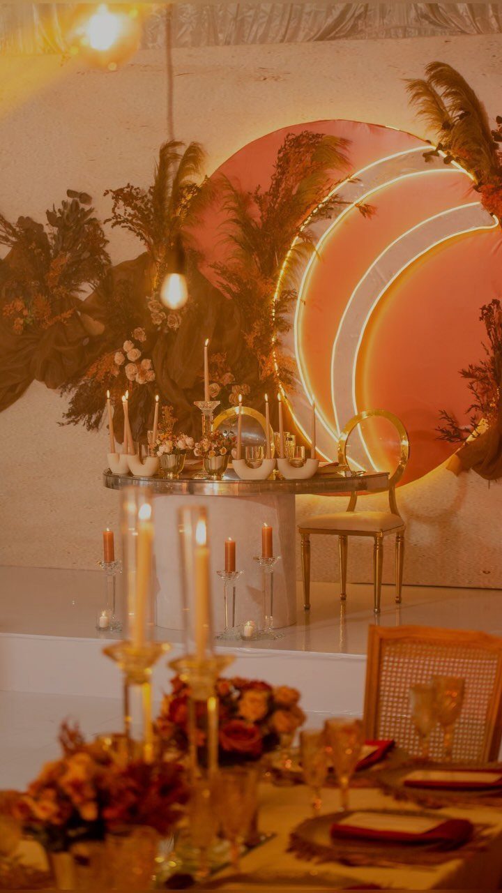 Fall Wedding Color Palette: 10 Ideas Photographed on Real Tables 2 Warmly lit wedding reception decor with orange circular backdrops, neon lights, and candlelit tables.