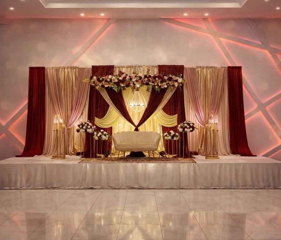 Fall Wedding Color Palette: 10 Ideas Photographed on Real Tables 3 Burgundy and gold draped curtains surround a white sofa on a decorated wedding stage.