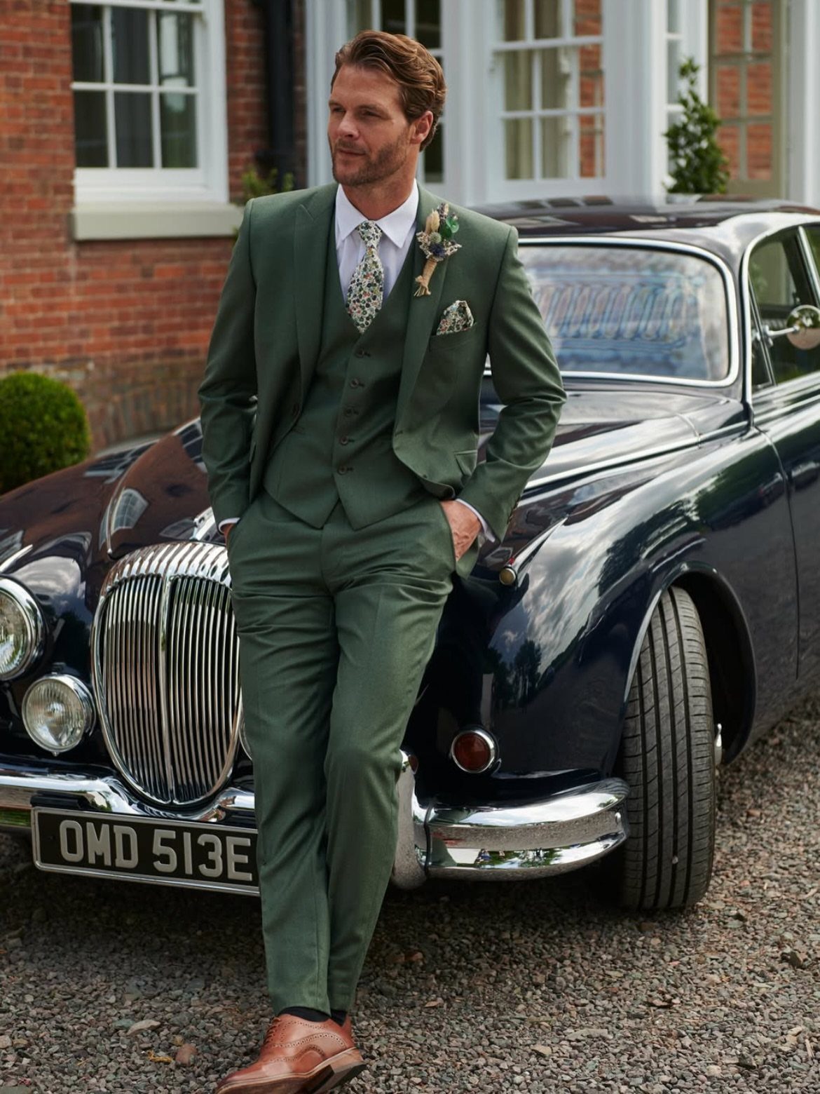 Green Wedding Suit: 8 Looks for Grooms and Guests 1 Man in a green three-piece suit leaning against a dark vintage car.
