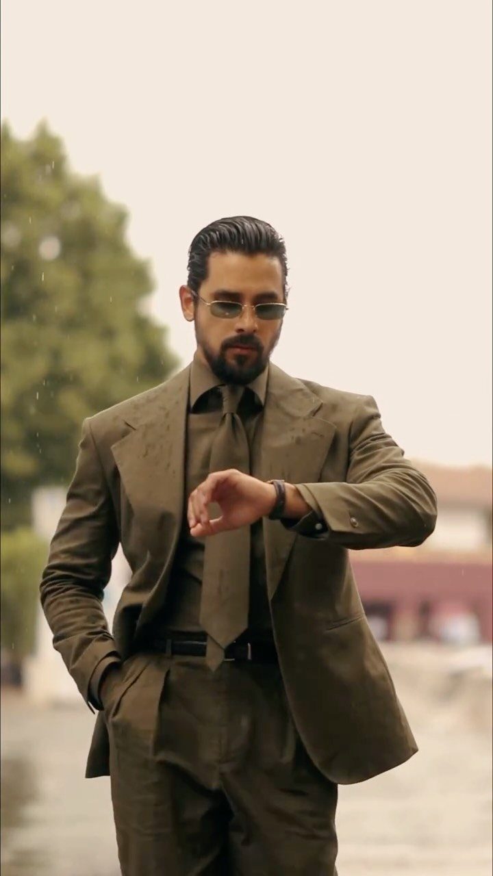 Green Wedding Suit: 8 Looks for Grooms and Guests 4 Man in an olive green three-piece suit checking his wristwatch outdoors.