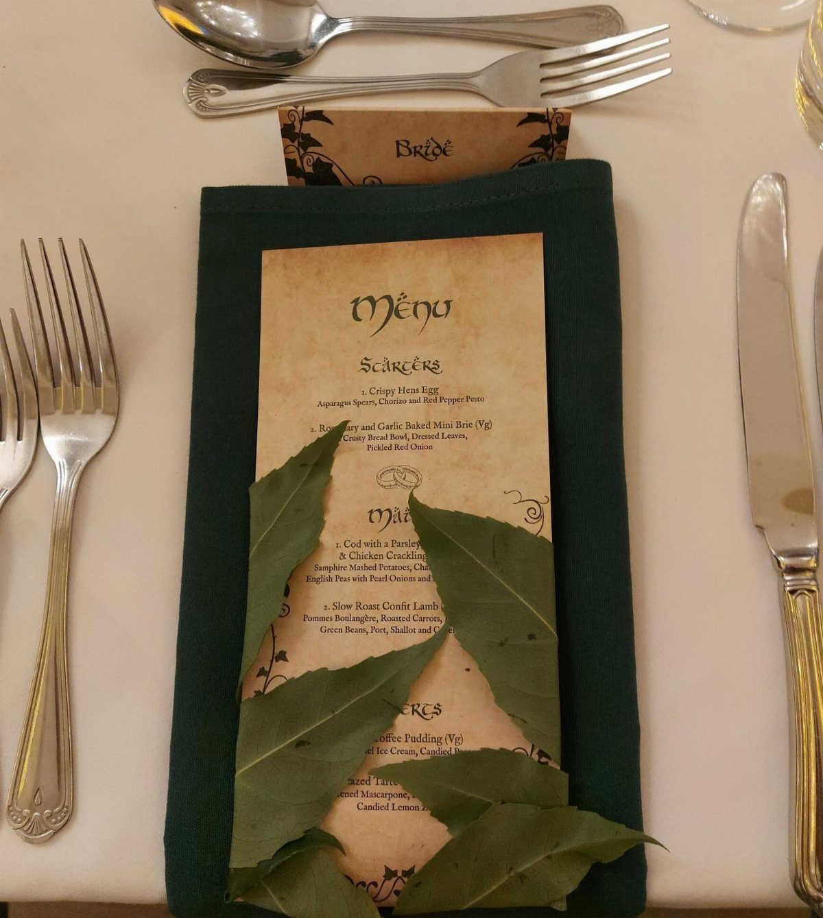 Hobbit Themed Wedding: 20 Ideas for Your Shire Celebration 18 A parchment menu with elven calligraphy resting on a green napkin with decorative leaves.