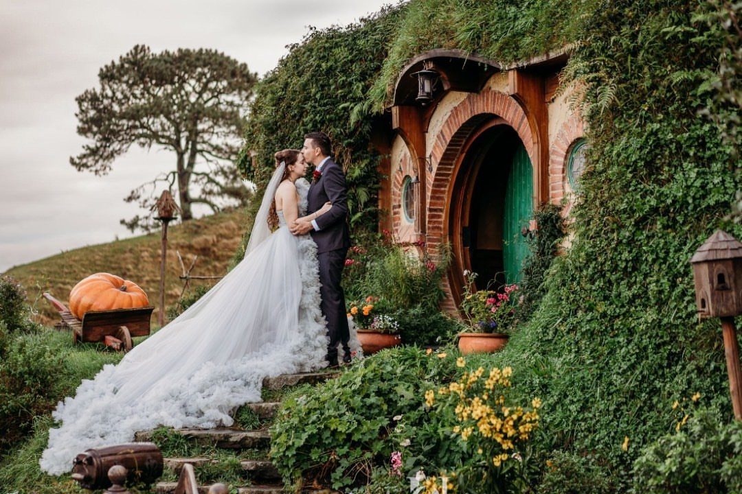Hobbit Themed Wedding: 20 Ideas for Your Shire Celebration 11 A bride and groom kissing in front of a green hobbit hole entrance.