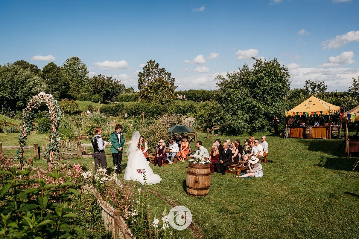 Hobbit Themed Wedding: 20 Ideas for Your Shire Celebration 7 A wedding ceremony held in a scenic, green outdoor garden with guests seated on benches.