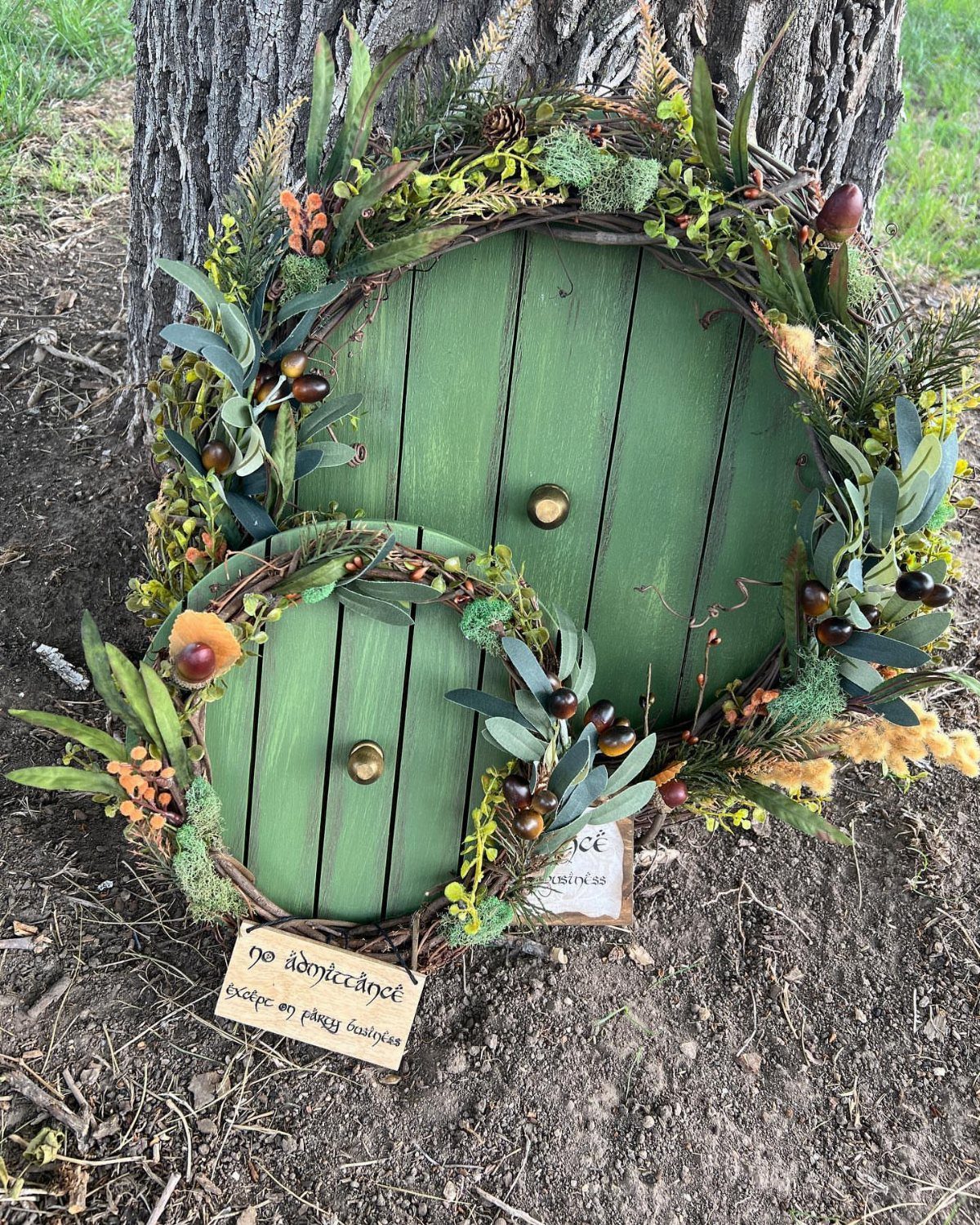 Hobbit Themed Wedding: 20 Ideas for Your Shire Celebration 19 Two round green wooden doors decorated with moss and greenery leaning against a tree trunk.
