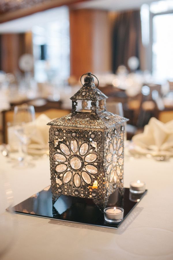 Lord of the Rings Centerpieces: 7 Tabletop Ideas for Your Event 2 Ornate silver metal lantern with intricate patterns sitting on a reflective base with tea lights.
