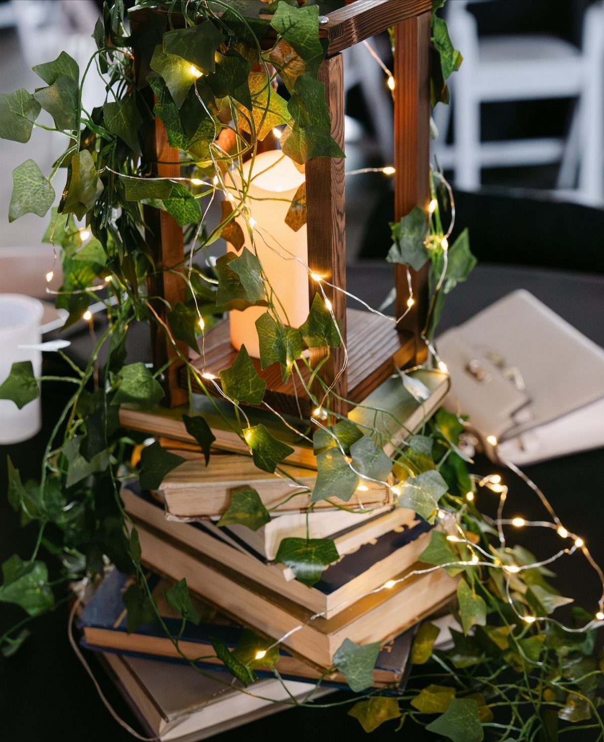 Lord of the Rings Centerpieces: 7 Tabletop Ideas for Your Event 3 A wooden lantern with a lit candle sits on a stack of old books wrapped in ivy.