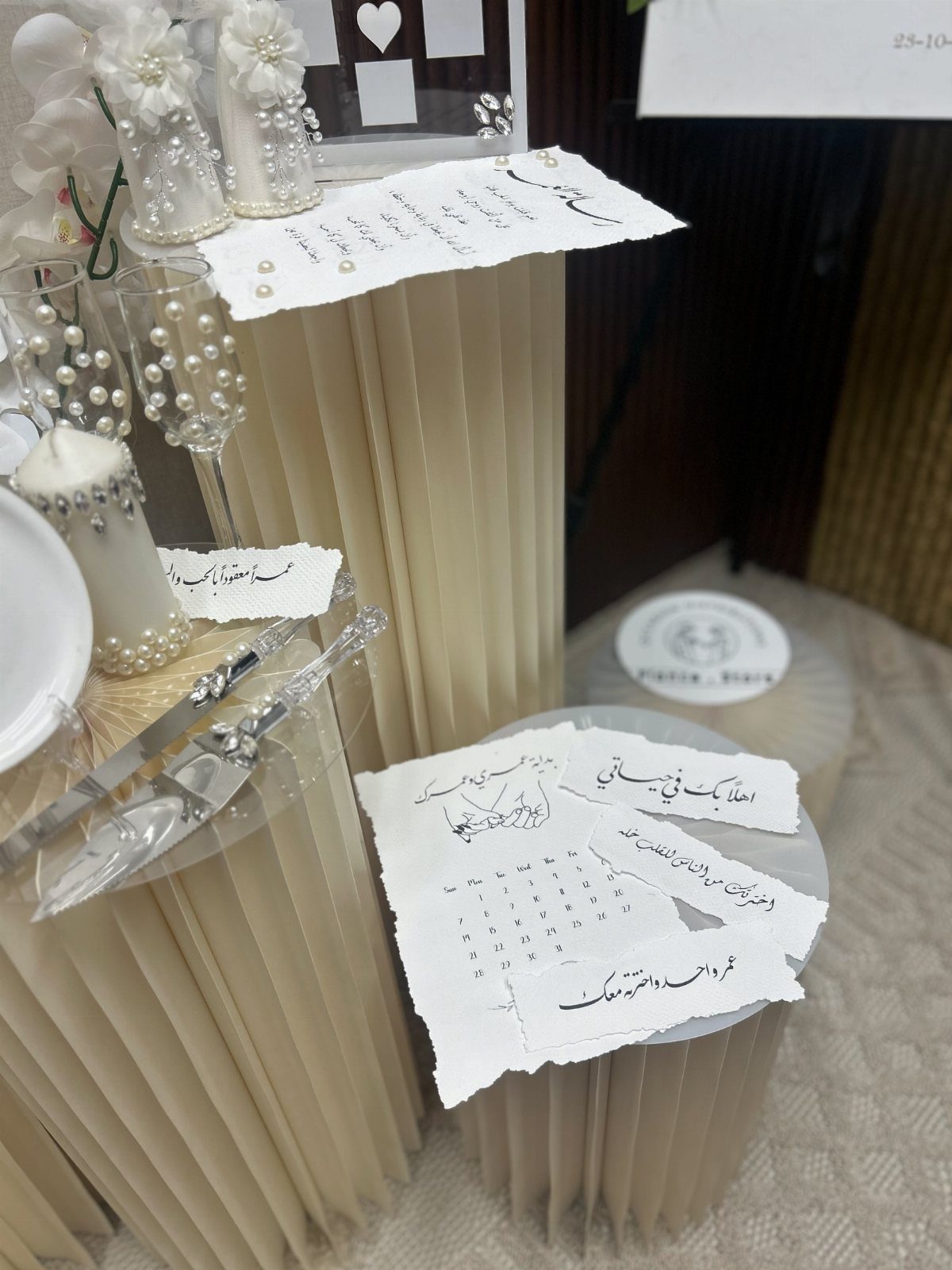 16 Marriage Theme Ideas for 2026: From Beach Ceremonies to Pearl Aesthetics 16 Elegant wedding decorations with pearl-embellished glassware and cream pleated pedestals on a table.