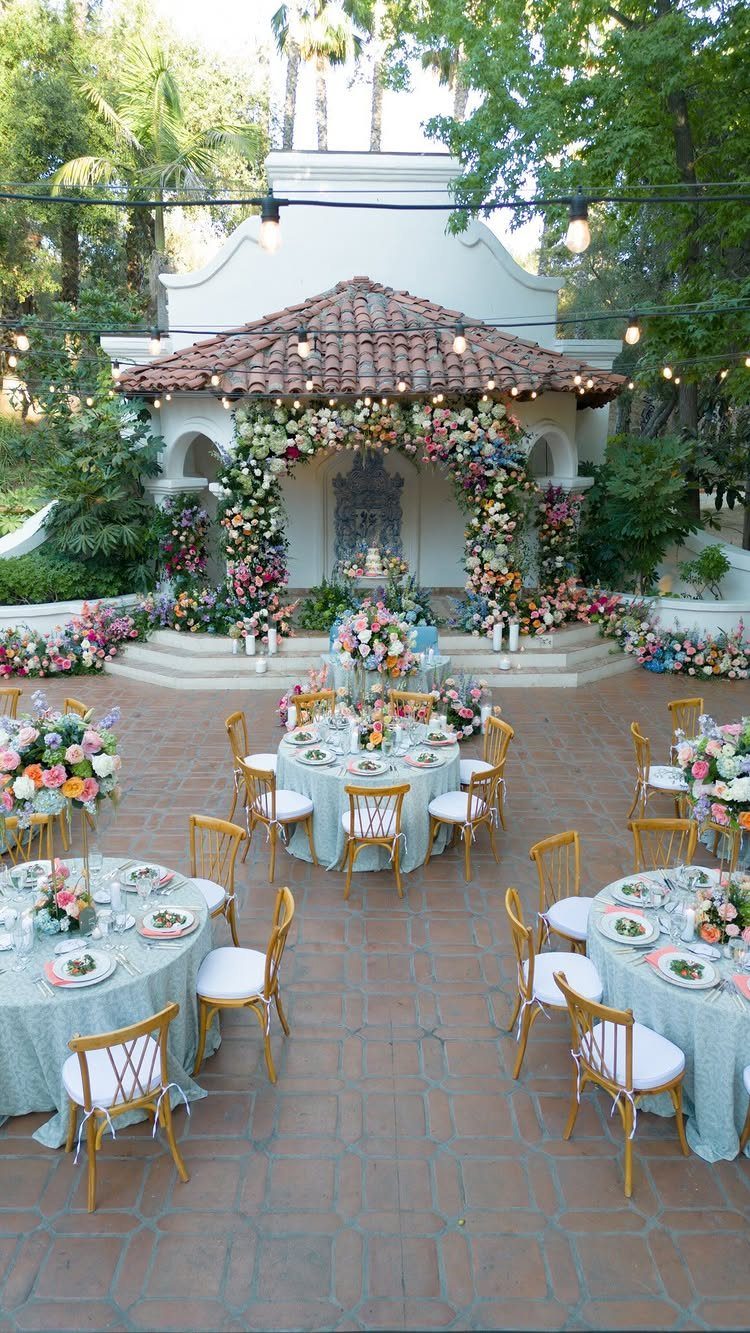 16 Marriage Theme Ideas for 2026: From Beach Ceremonies to Pearl Aesthetics 6 Outdoor wedding reception with round tables, light blue linens, and abundant, vibrant floral arrangements.
