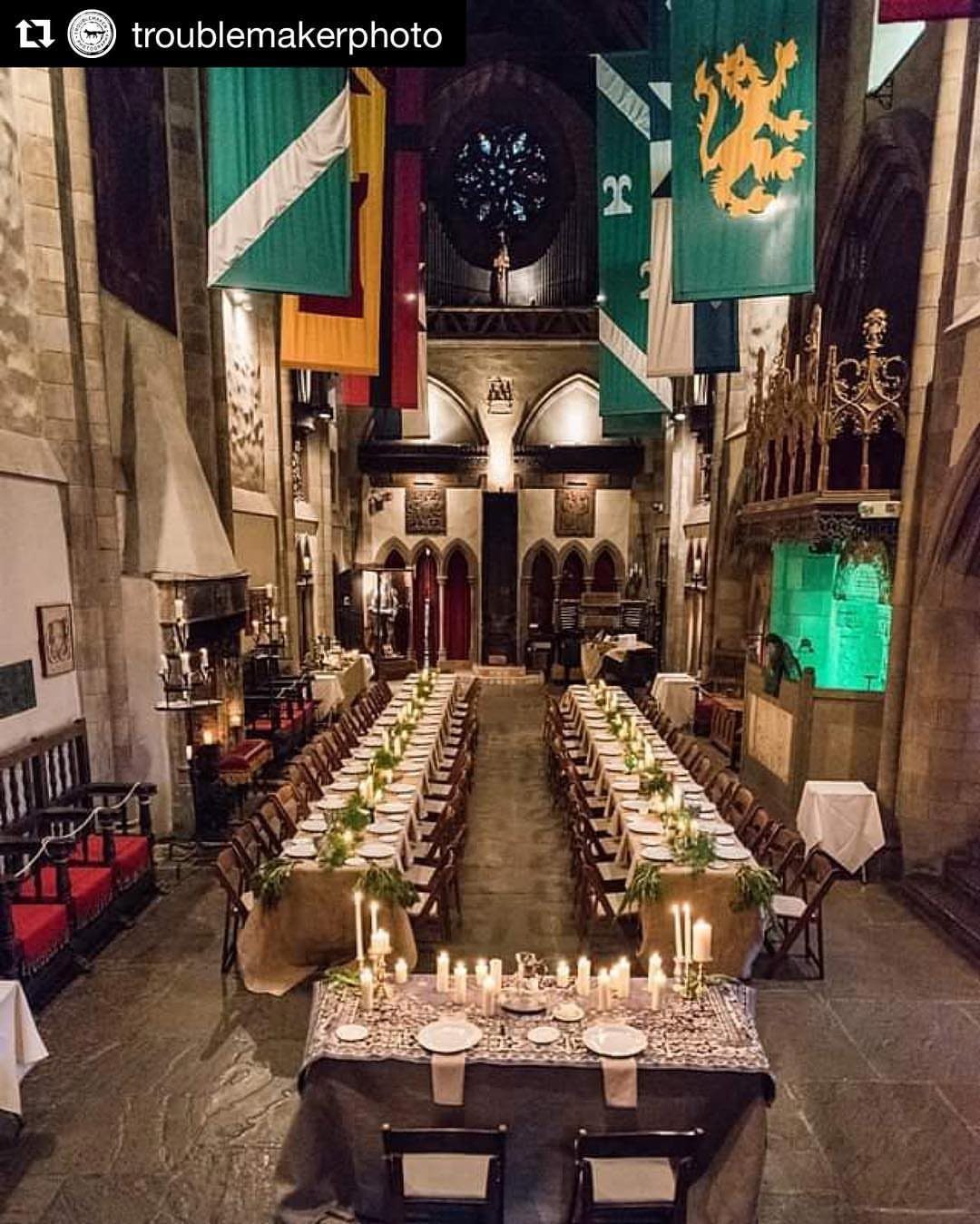 Medieval Wedding Theme: 7 Ideas for Your Day 3 Two long banquet tables set with candles and greenery inside a grand stone castle hall.