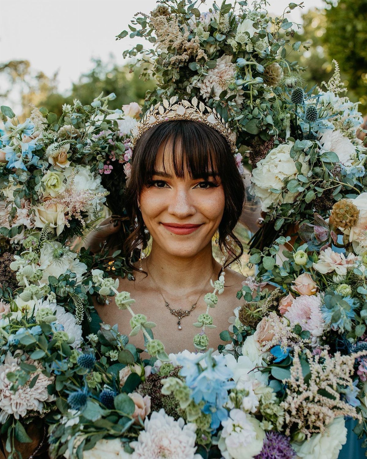 Medieval Wedding Theme: 7 Ideas for Your Day 7 A smiling woman wearing a gold leaf crown surrounded by a lush floral wreath.