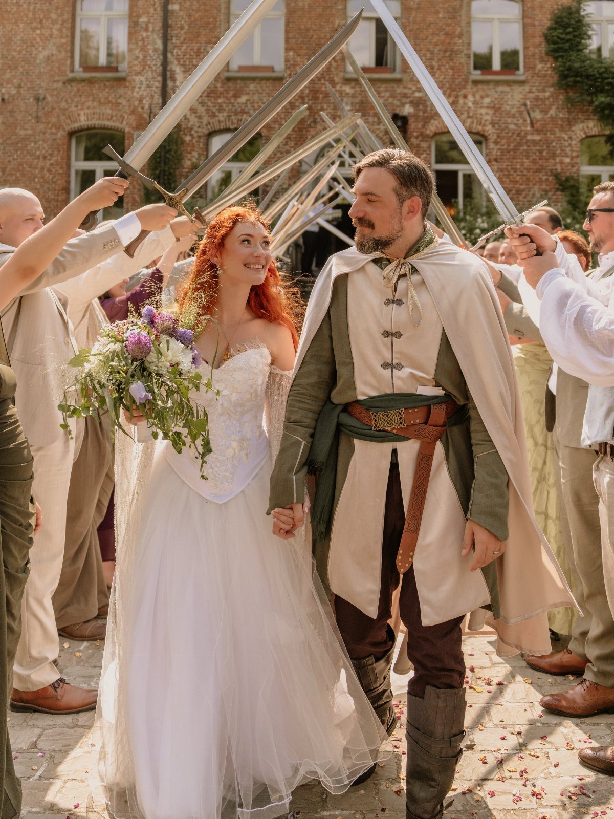 Medieval Wedding Theme: 7 Ideas for Your Day 1 A bride and groom walk through a ceremonial arch made of raised swords during a wedding.