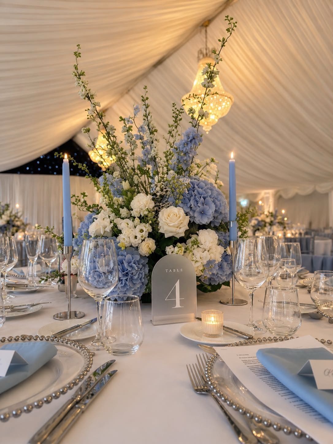 16 Navy Blue Wedding Theme Ideas for Every Part of Your Day 12 Blue hydrangea and white rose centerpiece with tall blue candles on a wedding table.