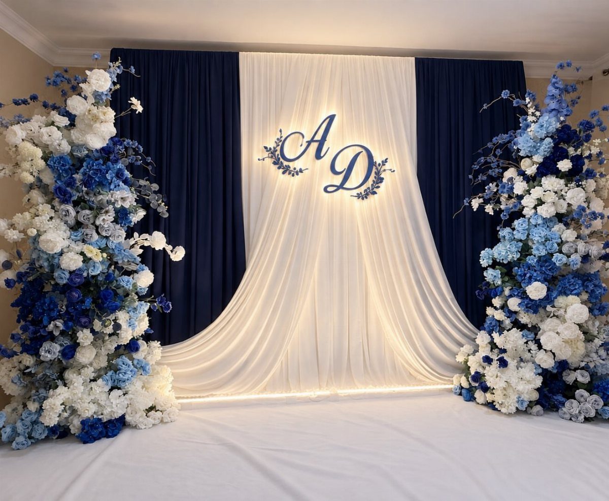 16 Navy Blue Wedding Theme Ideas for Every Part of Your Day 10 Navy blue and white draped fabric backdrop with large blue and white floral arrangements on the sides.