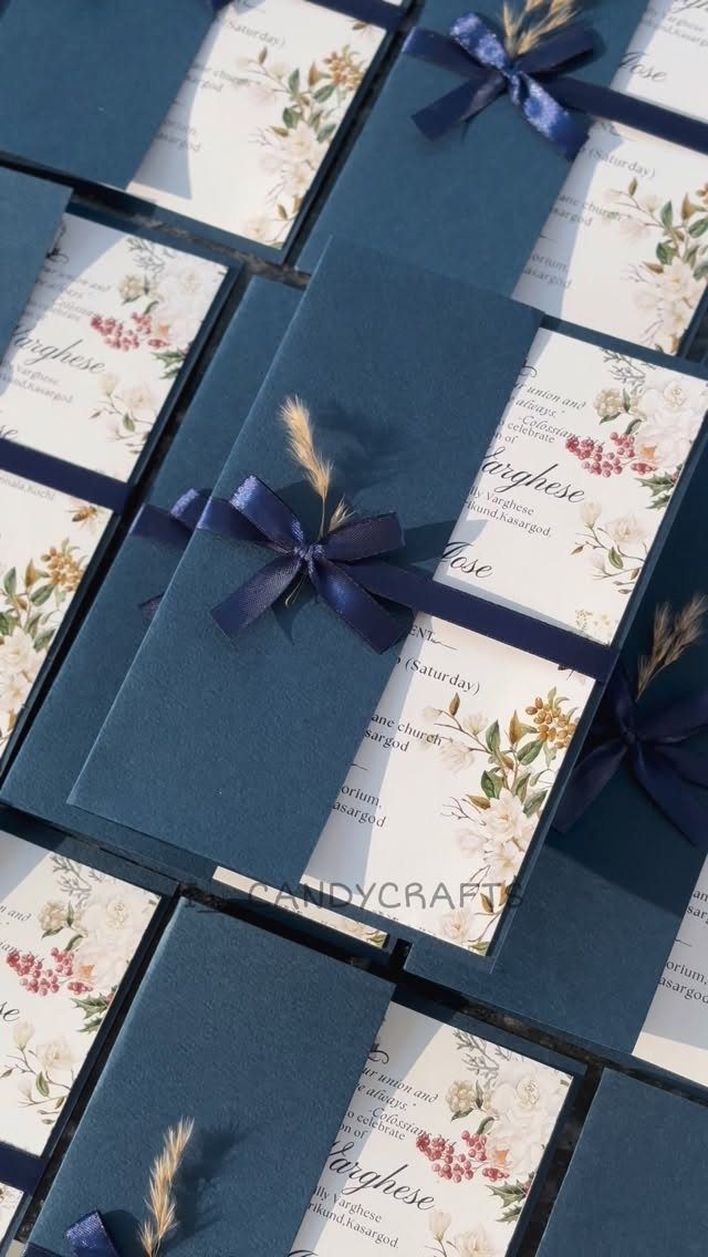 16 Navy Blue Wedding Theme Ideas for Every Part of Your Day 4 Navy blue wedding invitations with floral designs and navy ribbons tied with dried wheat stalks.
