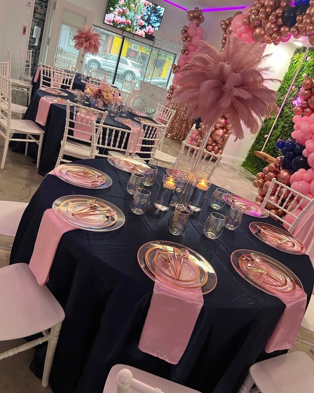 16 Navy Blue Wedding Theme Ideas for Every Part of Your Day 8 A navy blue wedding table setting with rose gold plates, pink napkins, and large pink feather centerpieces.
