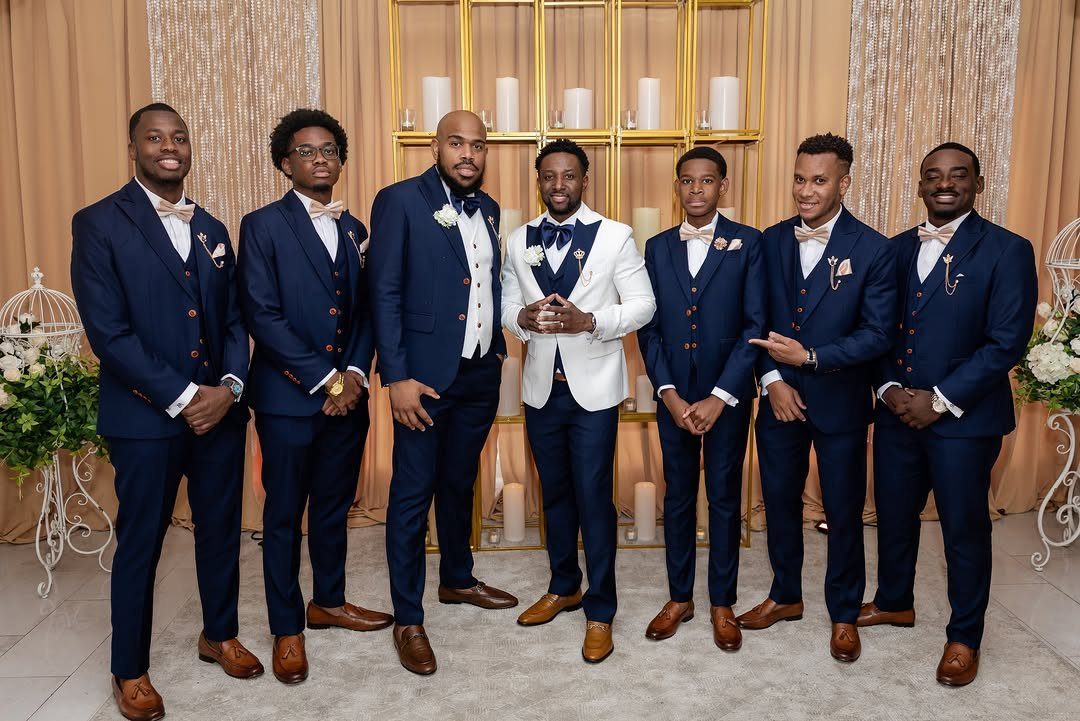 16 Navy Blue Wedding Theme Ideas for Every Part of Your Day 6 Seven men posing in navy blue and white wedding attire against a gold backdrop.