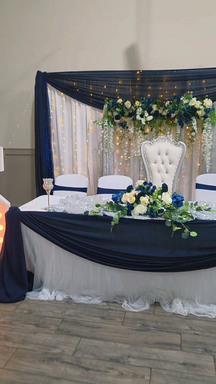 16 Navy Blue Wedding Theme Ideas for Every Part of Your Day 7 A wedding head table decorated with navy blue fabric, white tulle, and blue and white flowers.