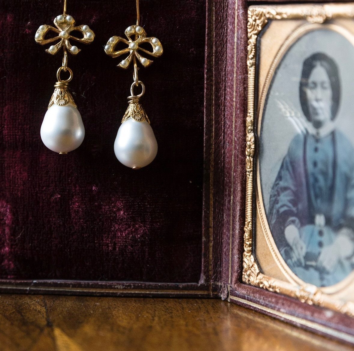 6 Pearl Drop Earrings Bridal Looks for Your Wedding Day 6 Gold teardrop earrings with large white pearls resting in a dark velvet jewelry box.