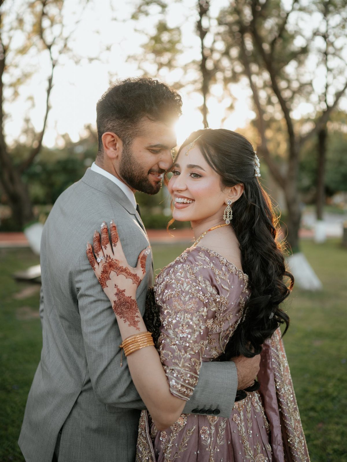 19 Photosession Ideas for Your Wedding Ceremony 1 A smiling couple embracing closely in a sunlit outdoor setting during golden hour.