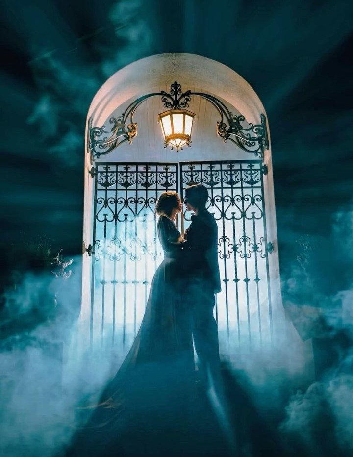 19 Photosession Ideas for Your Wedding Ceremony 8 Silhouetted couple embracing in front of a glowing arched gate amidst dramatic blue smoke.