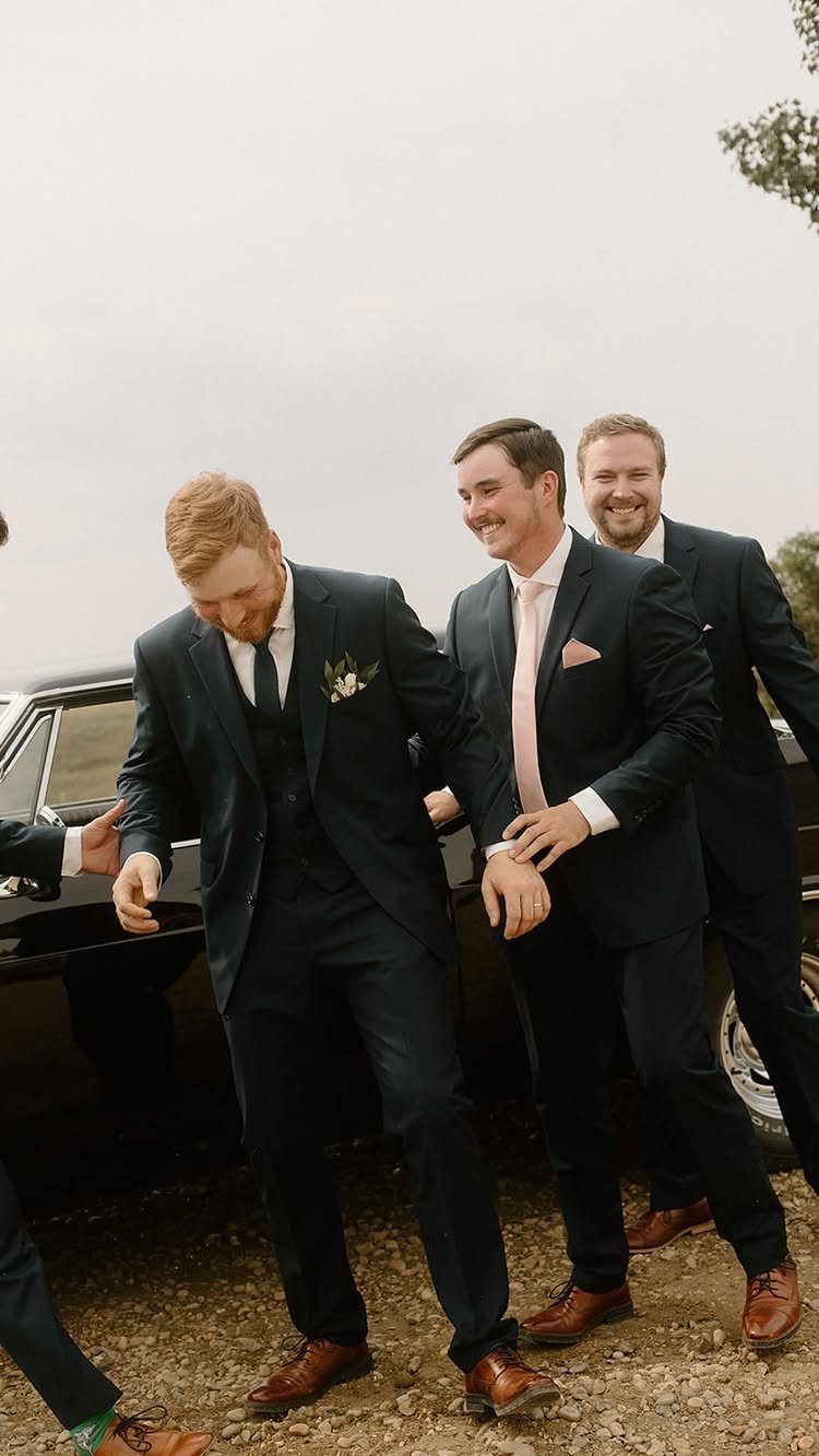19 Photosession Ideas for Your Wedding Ceremony 3 Groomsmen in navy suits laughing and posing next to a black vintage car.