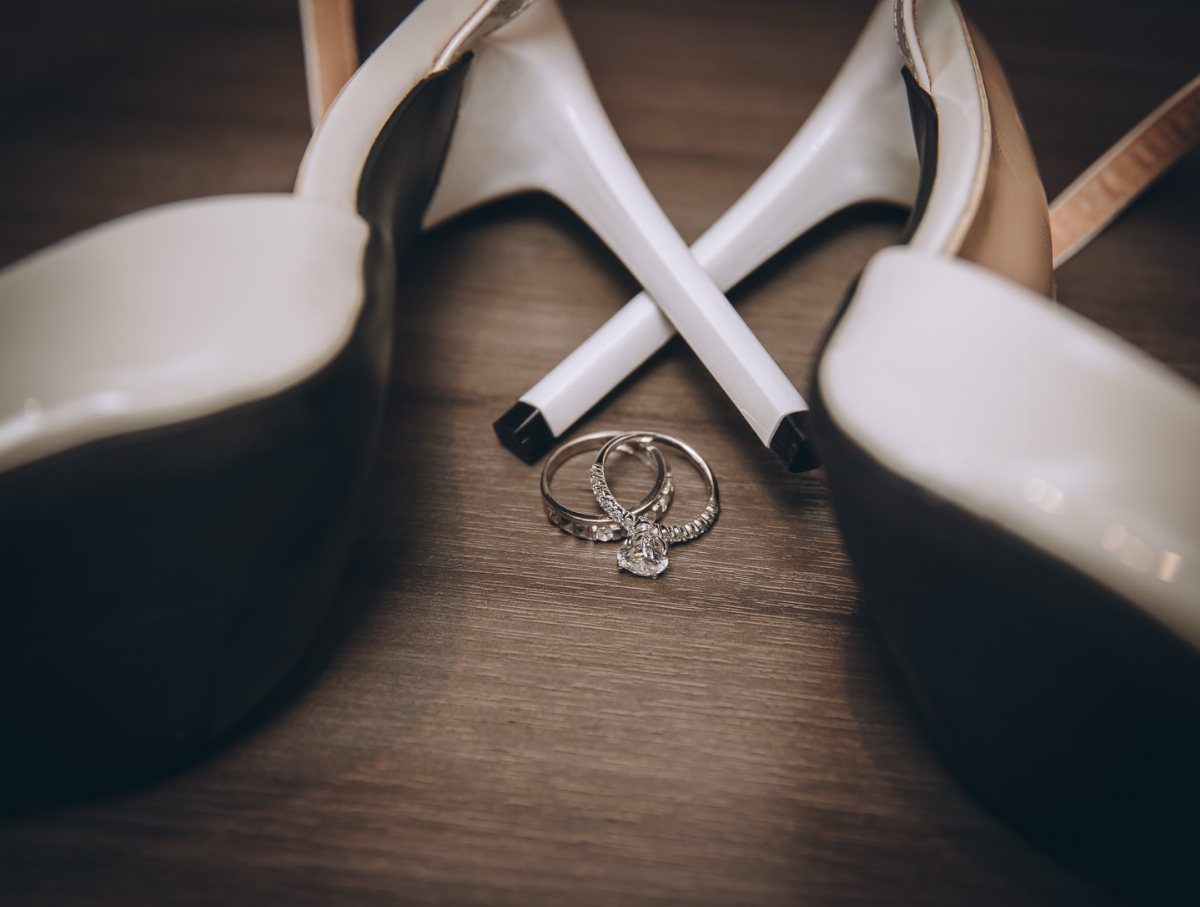 19 Photosession Ideas for Your Wedding Ceremony 4 Two diamond wedding rings resting on a wooden floor between white high-heeled shoes.