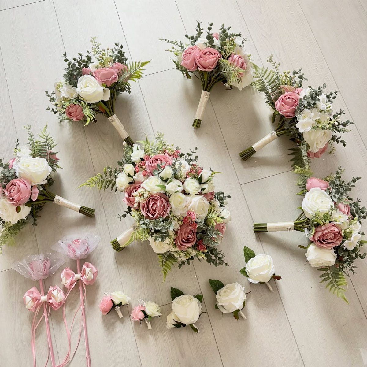 8 Pink Wedding Color Ideas for Every Venue and Season 2 Dusty rose and cream floral bouquets and boutonnieres arranged on a light wooden surface.