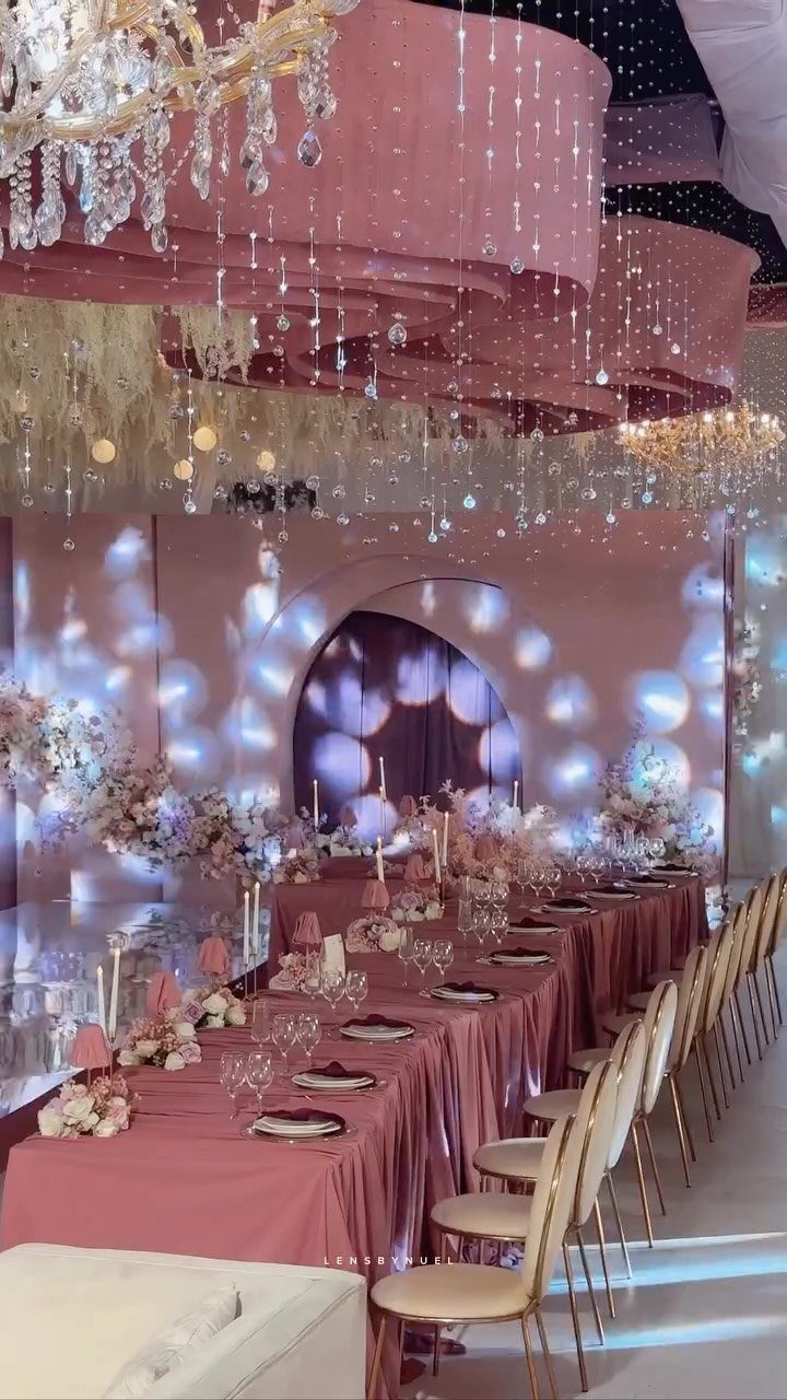 8 Pink Wedding Color Ideas for Every Venue and Season 1 A long banquet table decorated with dusty rose linens and white floral arrangements under crystal chandeliers.