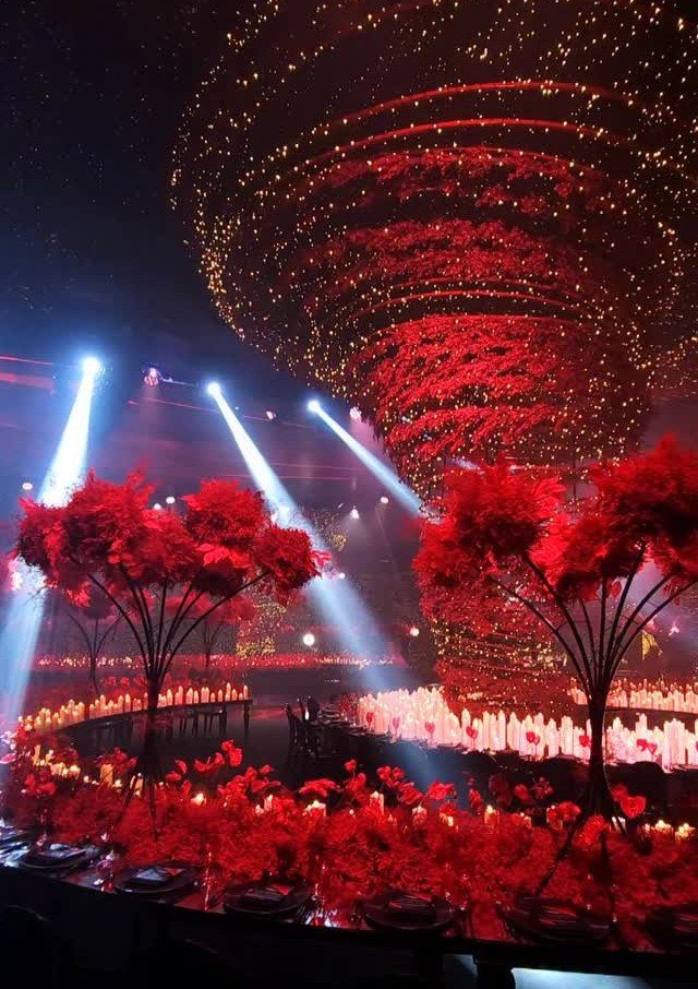 12 Romance Wedding Theme Ideas That Actually Feel Personal 3 Red floral arrangements and glowing candles illuminate a dark event space under swirling fairy lights.