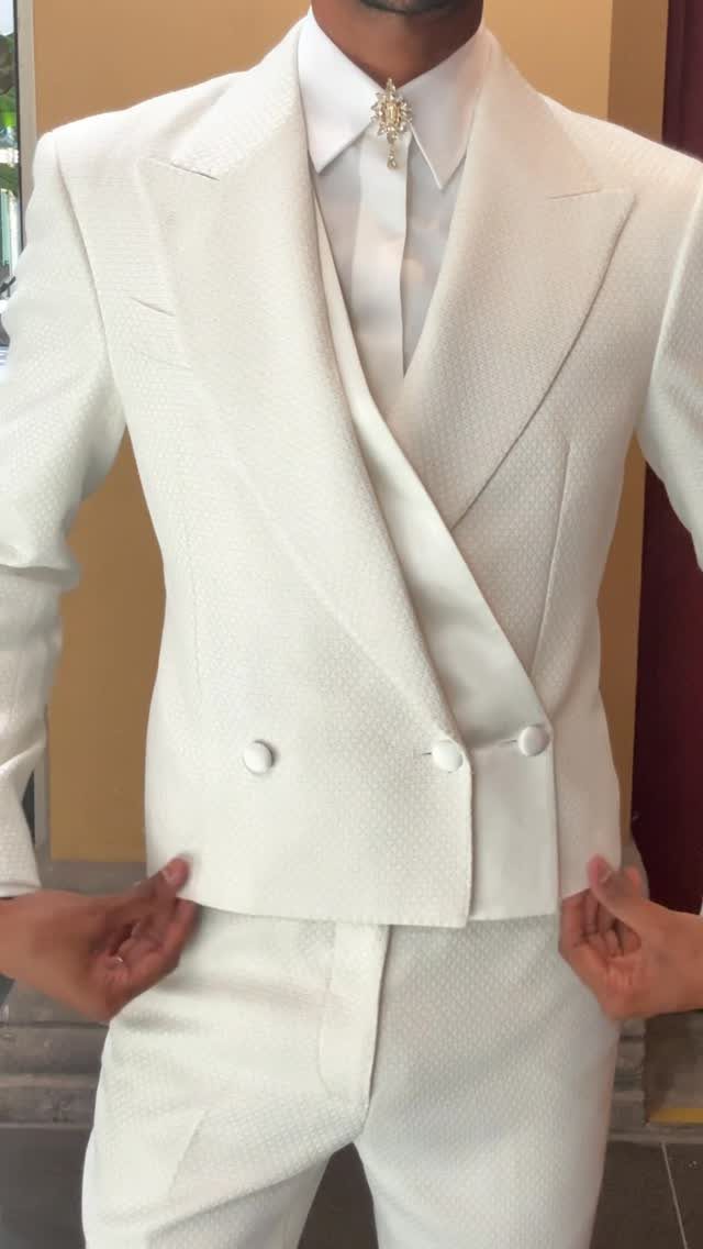 12 Romance Wedding Theme Ideas That Actually Feel Personal 7 Man wearing a white textured three-piece suit with a jeweled brooch on his shirt collar.