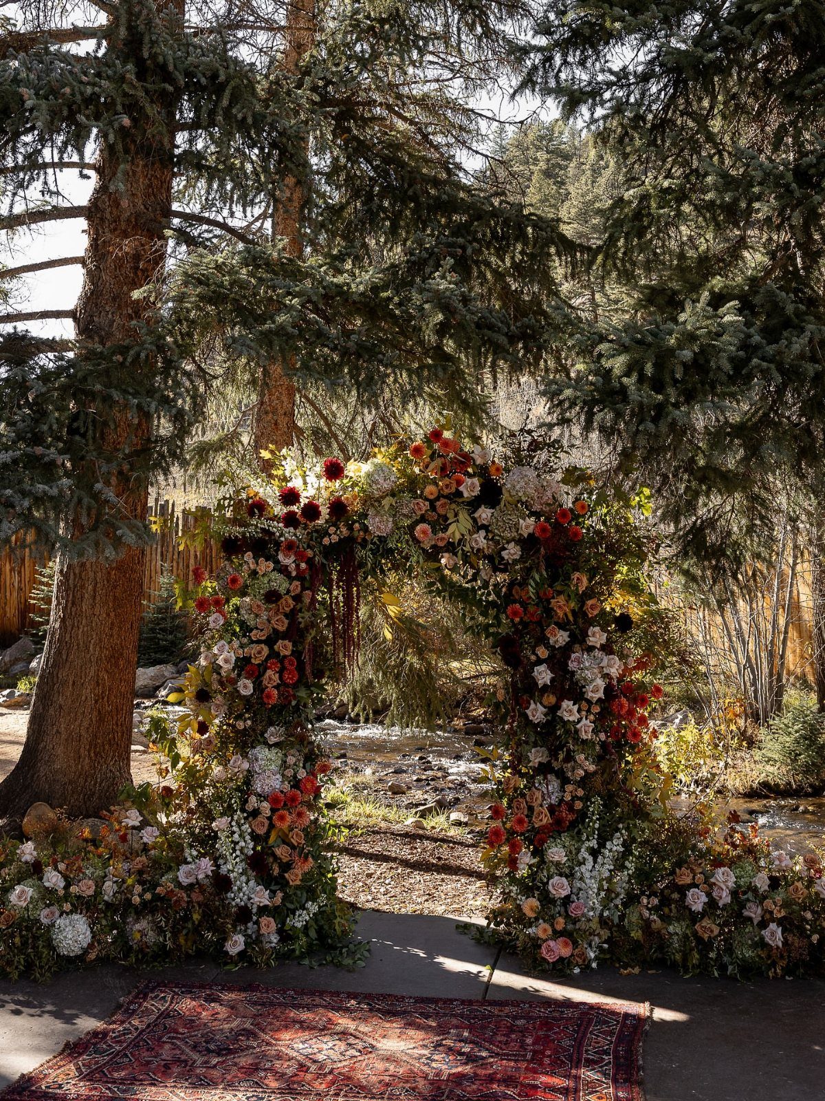 A patterned red rug lies on the ground leading toward a large floral archway outdoors.