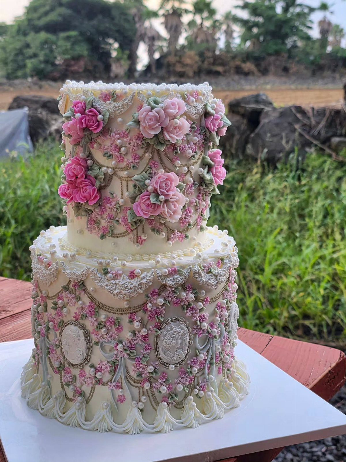 Two-tier vintage Lambeth-style cake with intricate pastel pink buttercream piping and sugar flowers.