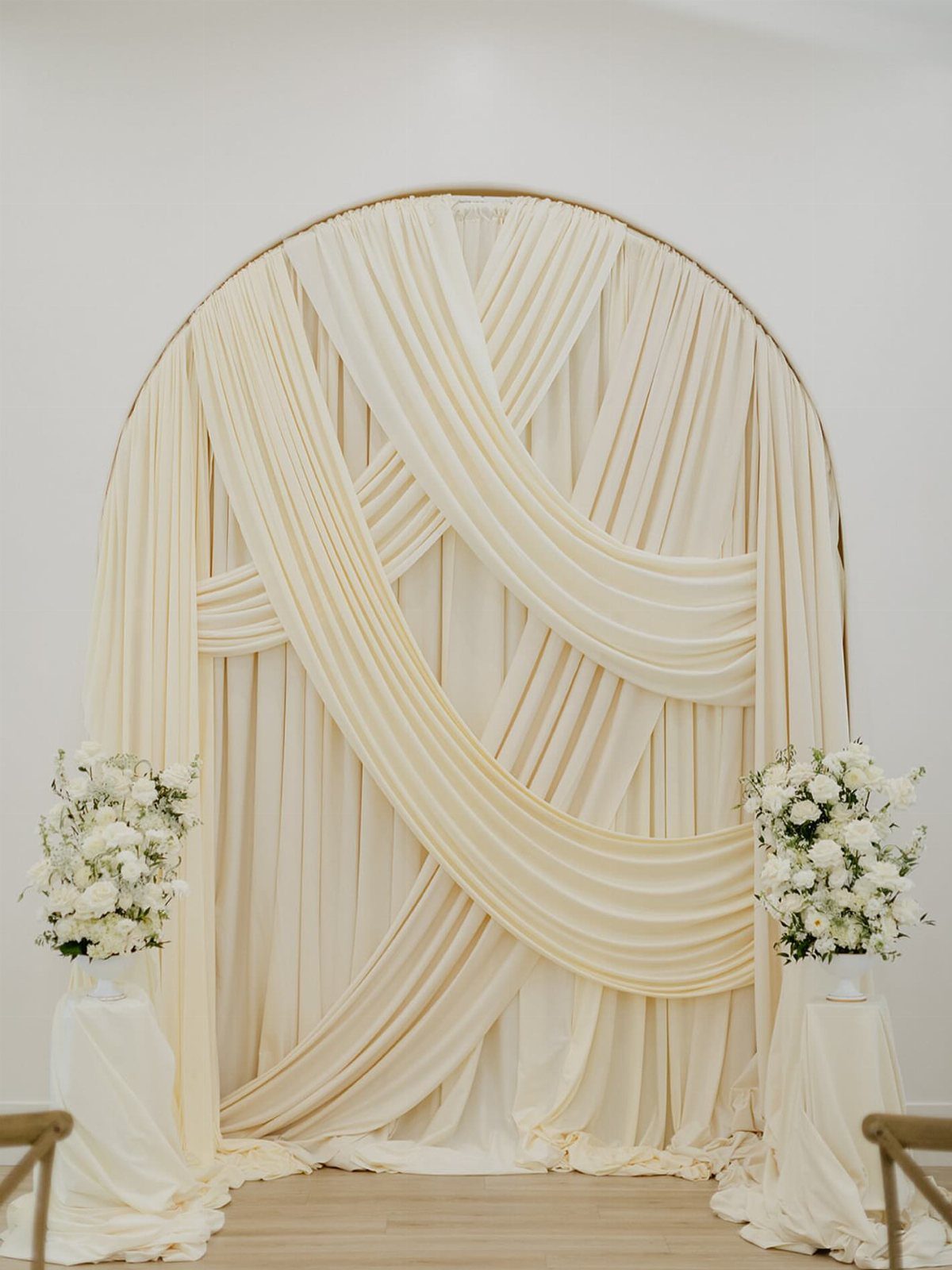 9 Wedding Ceremony Arch Ideas for Indoor and Outdoor Vows 1 Cream fabric draped in elegant swags over a large circular gold wedding arch.