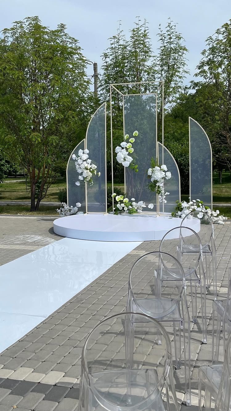 9 Wedding Ceremony Arch Ideas for Indoor and Outdoor Vows 3 A gold metal frame arch with translucent panels and white flowers on a white platform.