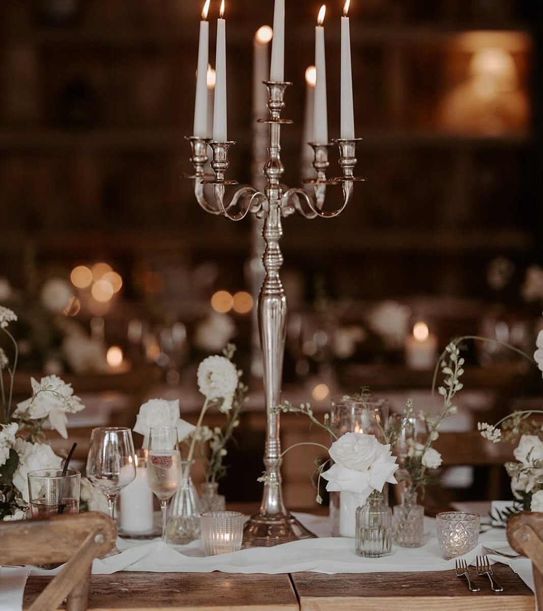 8 Wedding Decor Elegant Ideas for Church and Reception (2026) 5 Silver candelabra with five lit white taper candles on a decorated wedding reception table.