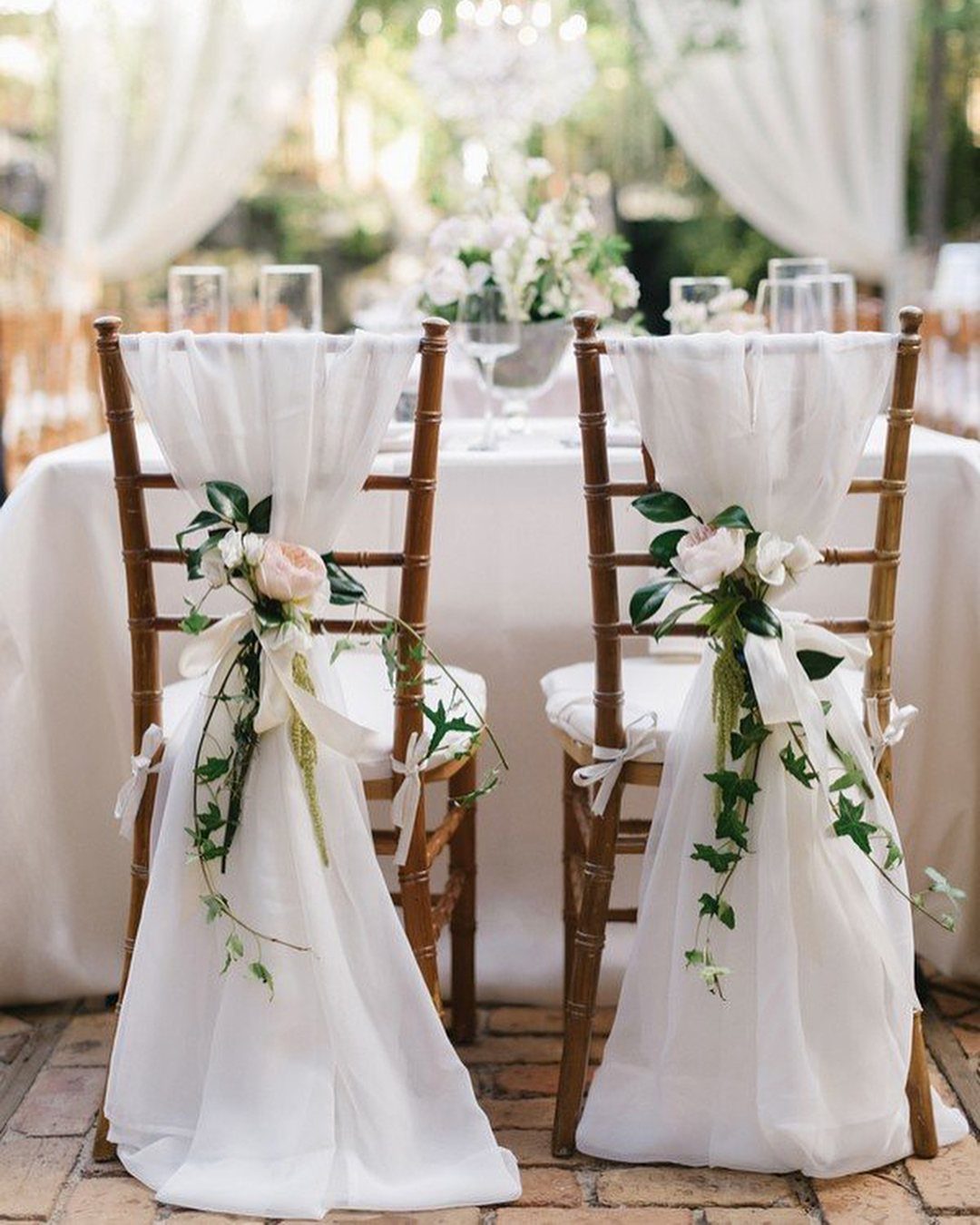 8 Wedding Decor Elegant Ideas for Church and Reception (2026) 6 Two wooden chairs decorated with white fabric sashes, white roses, and green leafy vines.