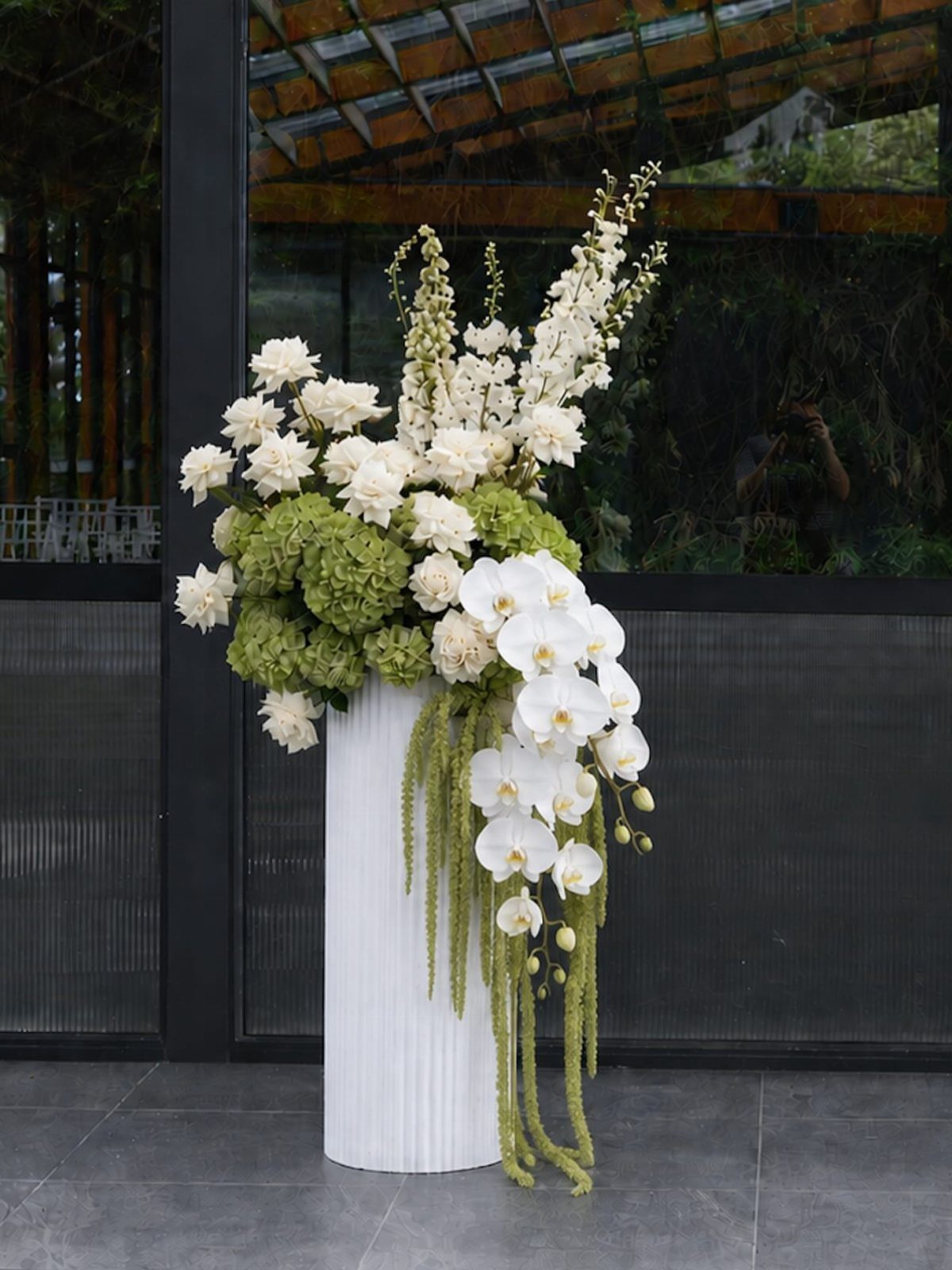 8 Wedding Decor Elegant Ideas for Church and Reception (2026) 1 Large white orchid and hydrangea floral arrangement in a tall white fluted vase.