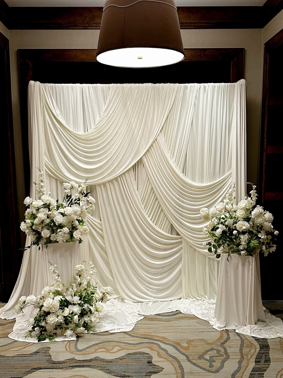 8 Wedding Decor Elegant Ideas for Church and Reception (2026) 2 White fabric draped in elegant swags with white floral arrangements on pedestals.