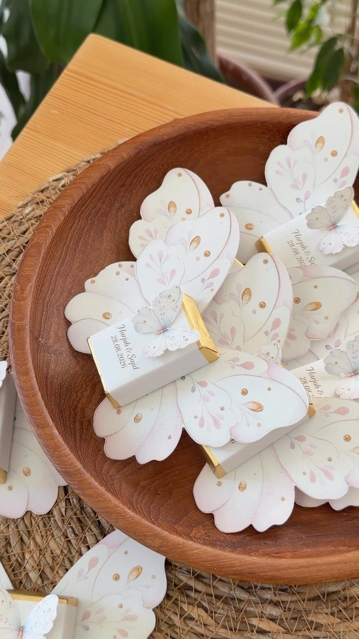 12 Wedding Events Ideas for Your Reception, Ceremony & More 9 White butterfly-themed favor boxes resting inside a large wooden bowl on a textured surface.
