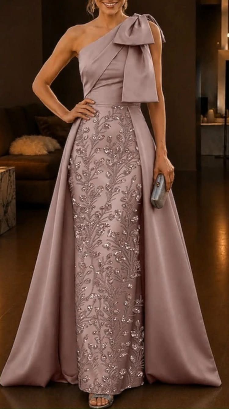 Woman posing in a mauve one-shoulder long dress with beaded floral details and a satin overskirt.